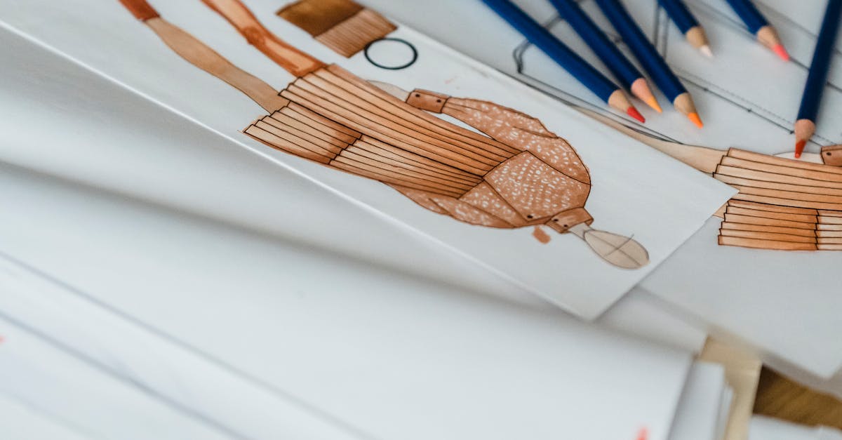 Close-up of fashion design sketches with pencils on a designer's desk.